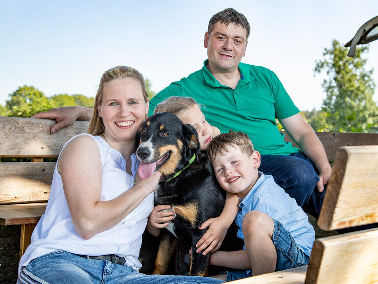 Familienhotel Landhus Laurenz im Münsterland: Familienfoto von Familie Laurenz auf altem Traktor mit Hund