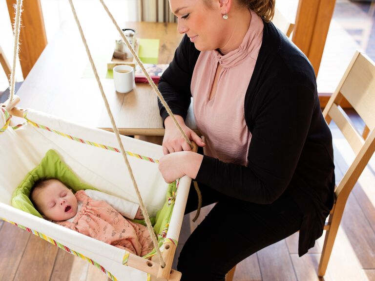 Familienhotel Landhus Laurenz im Münsterland: Eine Frau sitzt bei dem Baby, das in der Babyschaukel liegt
