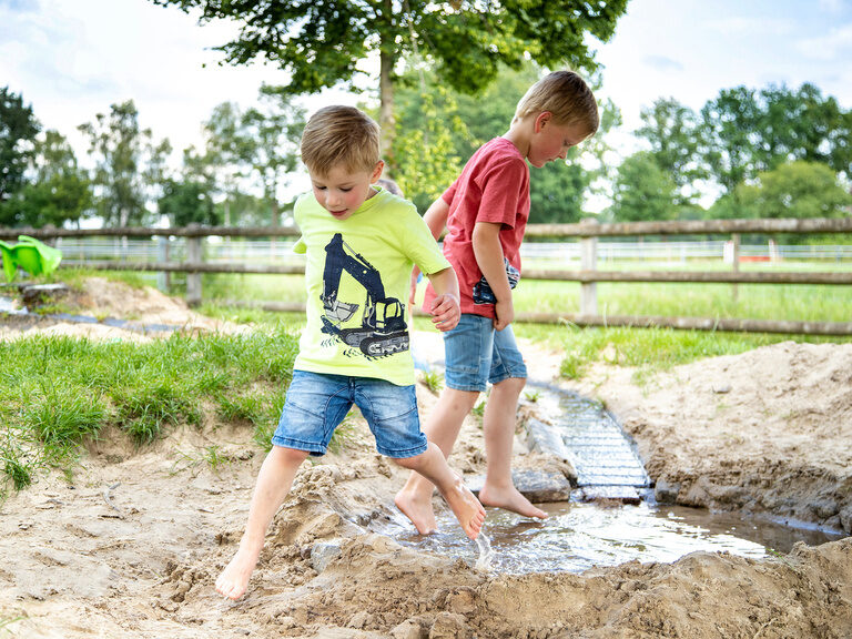 Familienhotel Landhus Laurenz im Münsterland: 2 Jungs spielen im Sand und haben einen Wassergraben gebaut